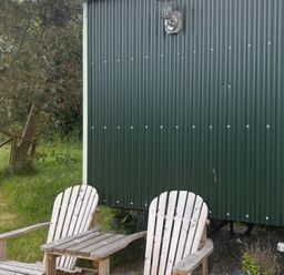 An outdoor area with a shepherd's hut, chairs, and a gravel path at Two Moors Shepherds Hut Hittisleigh