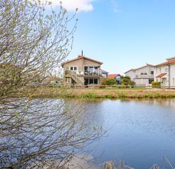 A body of water with houses and trees in the background at Links View in Fritton