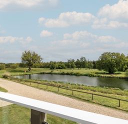 A view of a lake and trees from a balcony at Links View in Fritton