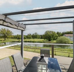 An outdoor area with a table and chairs overlooking a lake at Links View in Fritton