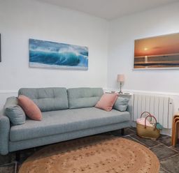 A living room with a sofa and wall art at Smugglers Cottage in Trebarwith Strand near Tintagel