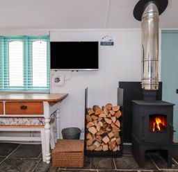 A living room with a fireplace and a television at Smugglers Cottage in Trebarwith Strand near Tintagel