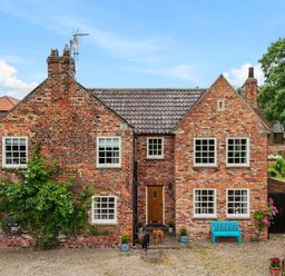 A brick house with multiple windows a wooden door and two dogs standing outside Manor Cottage Northallerton