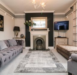 A living room with a sofa armchair fireplace mirror and television at Penlaurel in Launceston