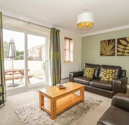 A living room with a brown leather sofa and armchair a wooden coffee table and two wall art pieces at Ladybird in Bridgwater