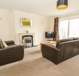 A living room with two brown leather sofas a fireplace a wall mirror a wooden coffee table and a television at Dragonfly in Bridgwater