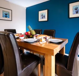 A dining room with a wooden table set with plates fruit and bread and dark brown chairs at Dragonfly in Bridgwater