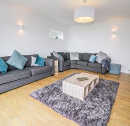 A living room with two gray sofas and blue cushions around a wooden coffee table on a gray rug at Hendre Wylan in Llanaber