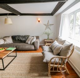 A living room with two sofas a wooden coffee table and large windows at Whitehall Farm Cottage in Honiton