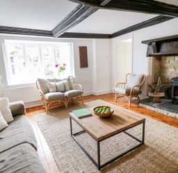 A living room with a fireplace wooden coffee table and cushioned seating at Whitehall Farm Cottage in Honiton