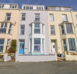 A row of multi-story terraced houses with bay windows and small front yards at 11 Marine Terrace in Criccieth