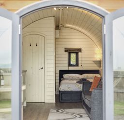 A view through open glass doors showing a bedroom with a bed and a couch at Corndon Pod White Grit near Chirbury