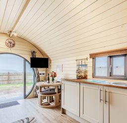 A kitchen and dining area with round window and sliding door leading outside at Corndon Pod in White Grit near Chirbury