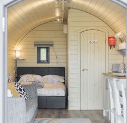 A small room with a bed sofa a wooden door and a kitchenette at Stiperstones Pod White Grit near Chirbury