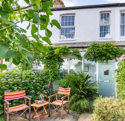 Front garden with two striped chairs and a small table in front of a white house with a green door at Downlea in Looe