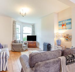 A living room with sofas a television a lamp and a painting at Downlea in Looe