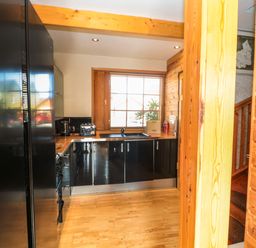 A kitchen with black appliances wooden countertops wooden floors and a window with blinds at Swallow Lodge in Amble