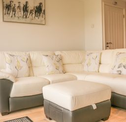 A living room with a sectional sofa with floral cushions and a matching ottoman at Upham View in Woodbury