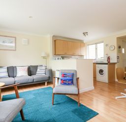 A living room with a sofa and chairs next to a kitchen and dining area at Pugwash Cottage in Falmouth