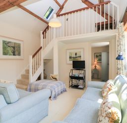 A living room with a sofa and television at Upper Mill Barn, Coln St Aldwyns, near Bibury