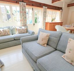 A living room with sofas and a dining area at Upper Mill Barn in Coln St Aldwyns near Bibury