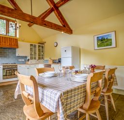 A kitchen with wooden chairs and a table with tablecloth and dishes at Little Barn in Ascott near Chipping Norton
