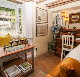 A small room with a wooden desk and chair a seating area with cushions and a window with shutters at Benfield in Stow-on-the-Wold