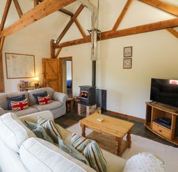 A living room with a wood stove and sofa at Robbie's Barn Fulready near Stratford-upon-Avon