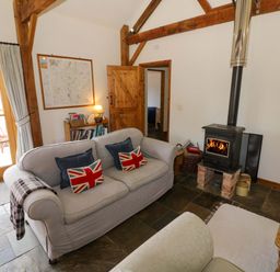 A living room with a wood stove and sofa at Robbie's Barn Fulready near Stratford-upon-Avon