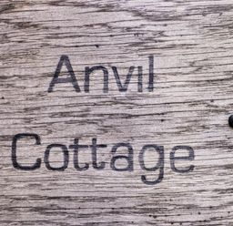 A wooden sign with the text Anvil Cottage