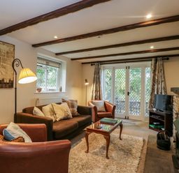 A living room with leather chairs a sofa a wooden coffee table and a stone fireplace at Anvil Cottage in Chipping Norton