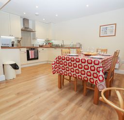 A kitchen with wood cabinets and a dining table with a red and white tablecloth at The Cottage At Barrow Mead in Bath