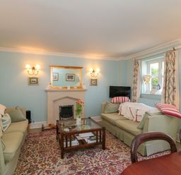 A living room with two sofas a coffee table a fireplace and a window at Batemans Nailsworth