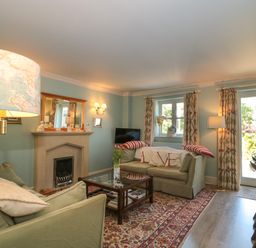A living room with sofas a fireplace a coffee table and a dining table at Batemans in Nailsworth