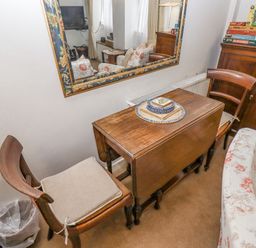 A small wooden table with two chairs and a mirror above it in a living room at Newbury Cottage in Bourton-On-The-Water