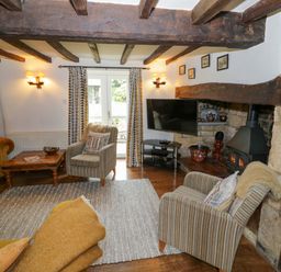 A living room with a sofa, armchair, and television at Elmhurst Cottage, Lower Quinton