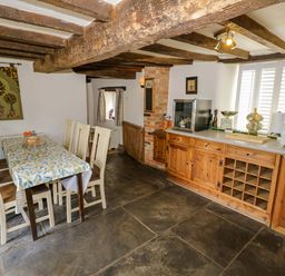 A kitchen with a dining table and cabinets at Elmhurst Cottage in Lower Quinton