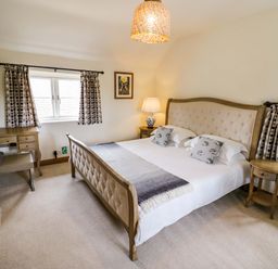 A bedroom with a bed and desk at Elmhurst Cottage in Lower Quinton