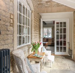 A sitting area with two chairs and a small table with flowers between two stone walls at South Hill Farmhouse in Stow-On-The-Wold