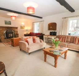 A living room with sofas a wooden coffee table and a stone fireplace at South Hill Farmhouse in Stow-On-The-Wold