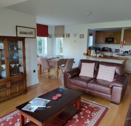 A living room with leather sofas a wooden coffee table and a display cabinet next to a dining area and kitchen at 5 Burford Mews in Burford
