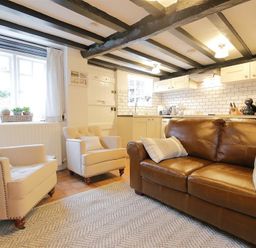 A living room with two armchairs a leather sofa and a kitchen in the background at One Masons Court in Stratford upon Avon