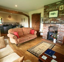 A living room with sofas a brick fireplace and an open kitchen at The Piggery in Lydney