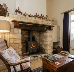 A living room with a fireplace and armchair at The Old Reading Room in Bledington near Stow-on-the-Wold