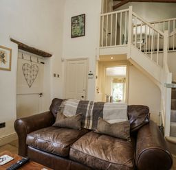 A living room with a sofa and staircase at The Old Reading Room in Bledington near Stow-on-the-Wold