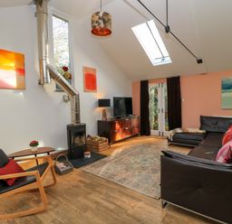 A living room with a sofa, coffee table, and television at The Linhay in Little Coxwell near Faringdon