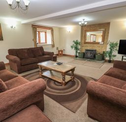 A living room with a fireplace and seating at Tithe Barn, Lyneham