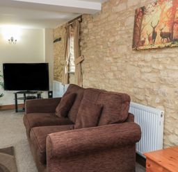 A living room with a sofa and television at Tithe Barn, Lyneham