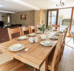 A dining room with a large table set for meals at Tithe Barn, Lyneham