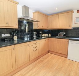 A kitchen with wooden cabinets and appliances at Tithe Barn, Lyneham